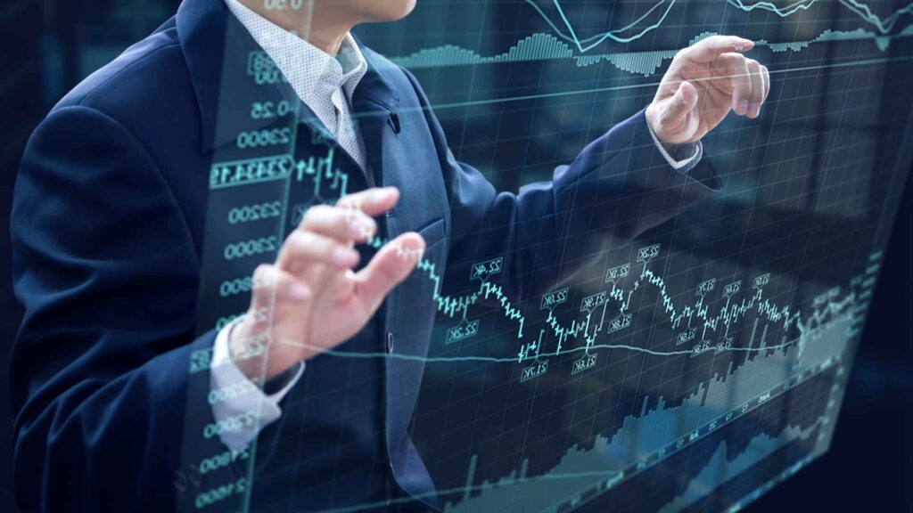 Businessperson studies fluctuating stock charts on a transparent digital screen, symbolizing innovation in investing.